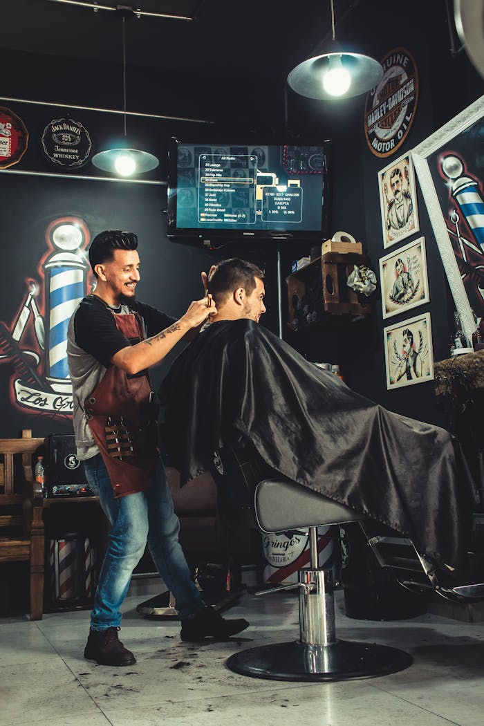 Home A barber skillfully cutting a man's hair in a trendy, well-decorated barbershop.
